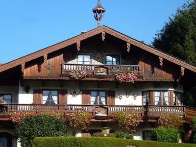 Двухэтажный деревянный дом в баварском стиле с белой штукатуркой и темным  деревом