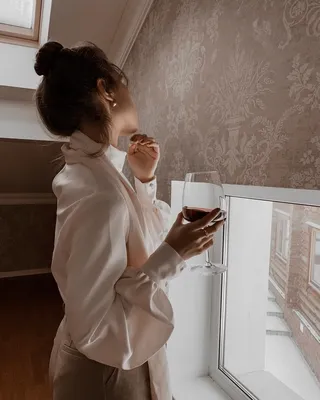 Изображение бокала вина в руке на фоне деревянного дома