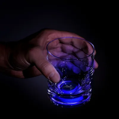 Фотография бокала виски в руке на черном фоне