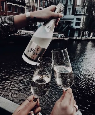 Руки, держащие бокалы с шампанским на фоне заката над морем