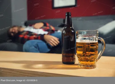 Бутылка и кружка пива на столе и размытым пьяный человек спит на диване у  себя дома. Концепция алкоголизма :: Стоковая фотография :: Pixel-Shot Studio