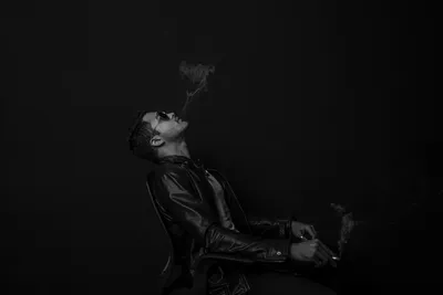 Задумчивый молодой этнический парень курит сигарету возле обшарпанной стены  · Бесплатные стоковые фото