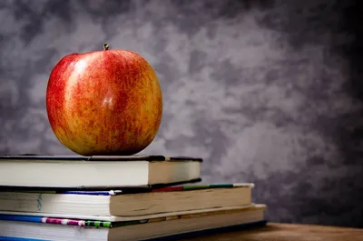 Школьные учебники с яблоком, канцелярскими принадлежностями и будильником  на столе на белом фоне :: Стоковая фотография :: Pixel-Shot Studio