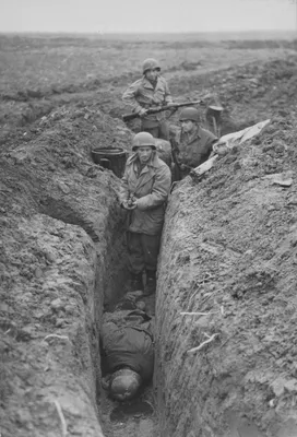 Трое американских солдат у лежащего в окопе тела солдата вермахта — военное  фото