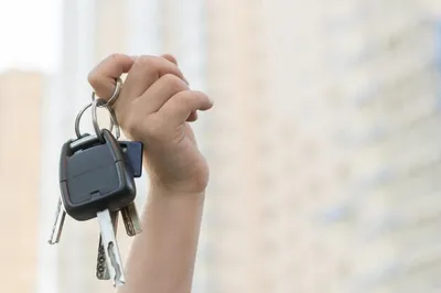 Руки с ключами от машины на сером фоне