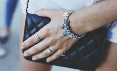 Кольца Пандоры на руке на фоне серебряного браслета