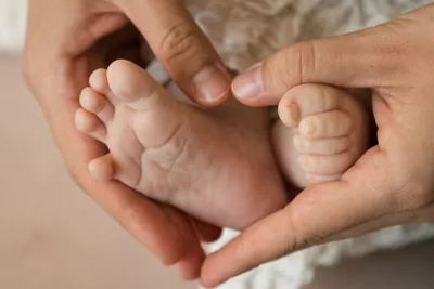Новорожденный на руках с маленькими ножками