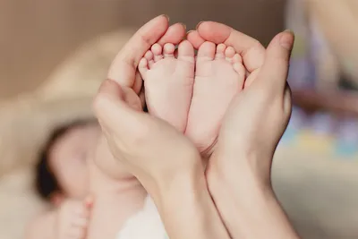 Нежные ножки младенца в руках