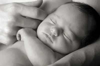 Изображение маленьких ножек новорожденного в маминых руках
