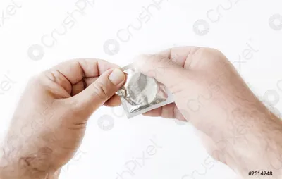 Фотография руки, держащей презерватив