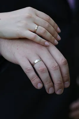 Фотография обручальных колец на пальцах молодоженов