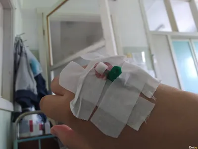 Фотография медицинской капельницы и рук в больнице