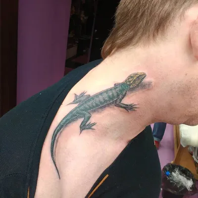 Изображение татуировки ящерицы на руке на фоне природы