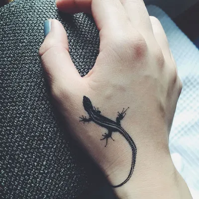 Изображение татуировки ящерицы на руке на черном фоне