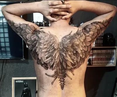 Фото татуировки крылья на руке на черном фоне