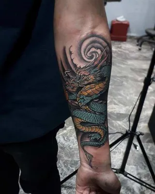 Изображение тату на руке дракона с красочными цветами