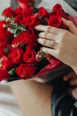 Женской руки с кольцом и цветами фотографии