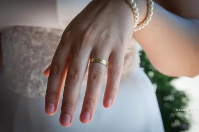 Фото женской руки с обручальным кольцом на фоне природы
