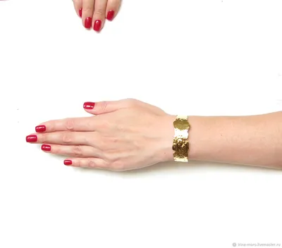 Картинка женской руки с золотым браслетом на фоне природы